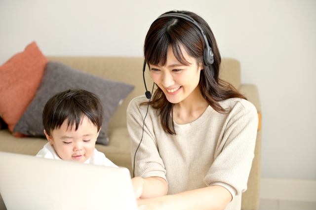 子どものそばでWebライターの仕事をする女性